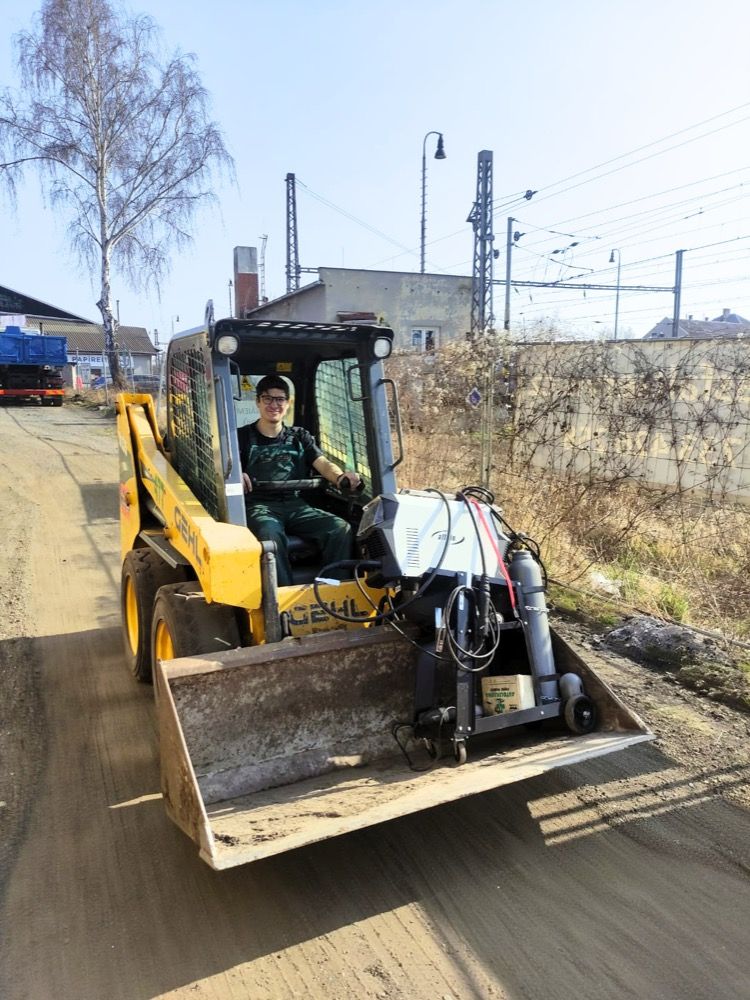 Člen týmu řídí smykový nakladač v provozu